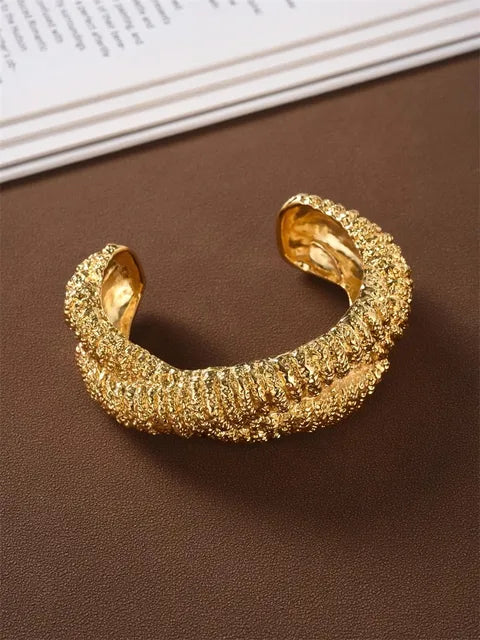 Gold open cuff bracelet with a heavy, textured, bumpy metal surface and smooth polished inner sides.