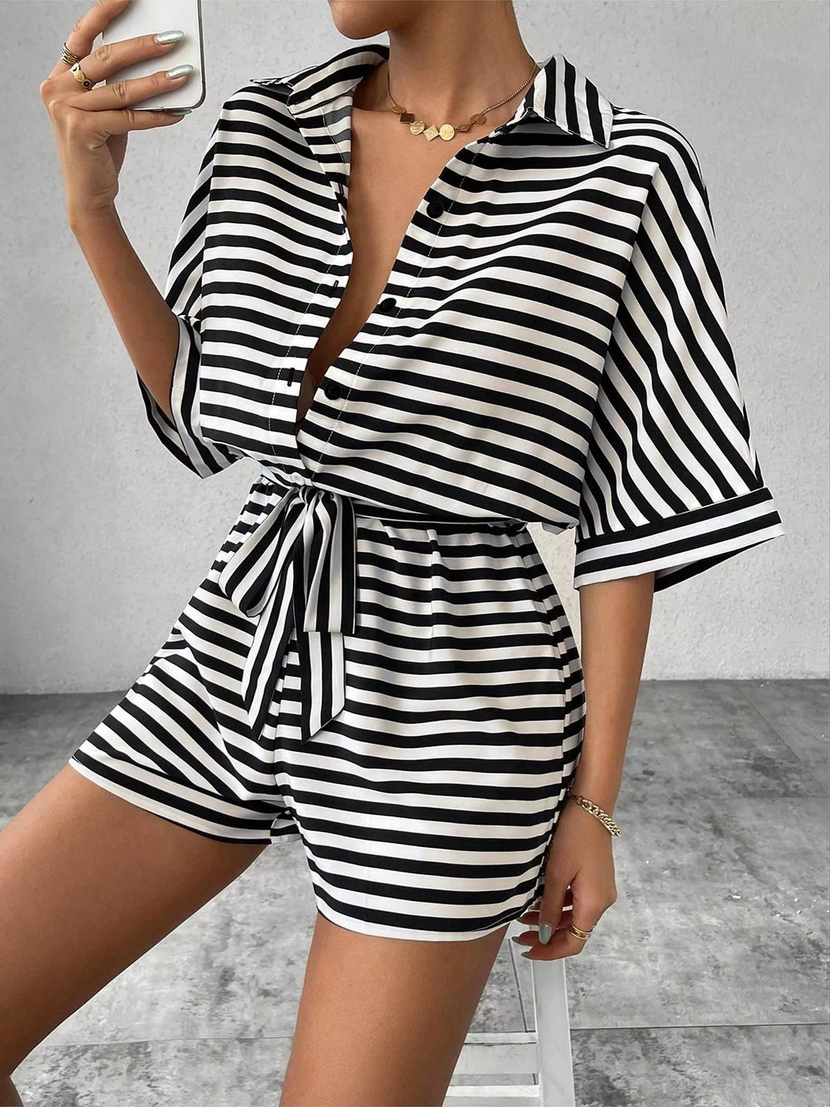 Striped button-up belted romper jumpsuit by Plush Fashion Hub, featuring a stylish design and fitted waist.