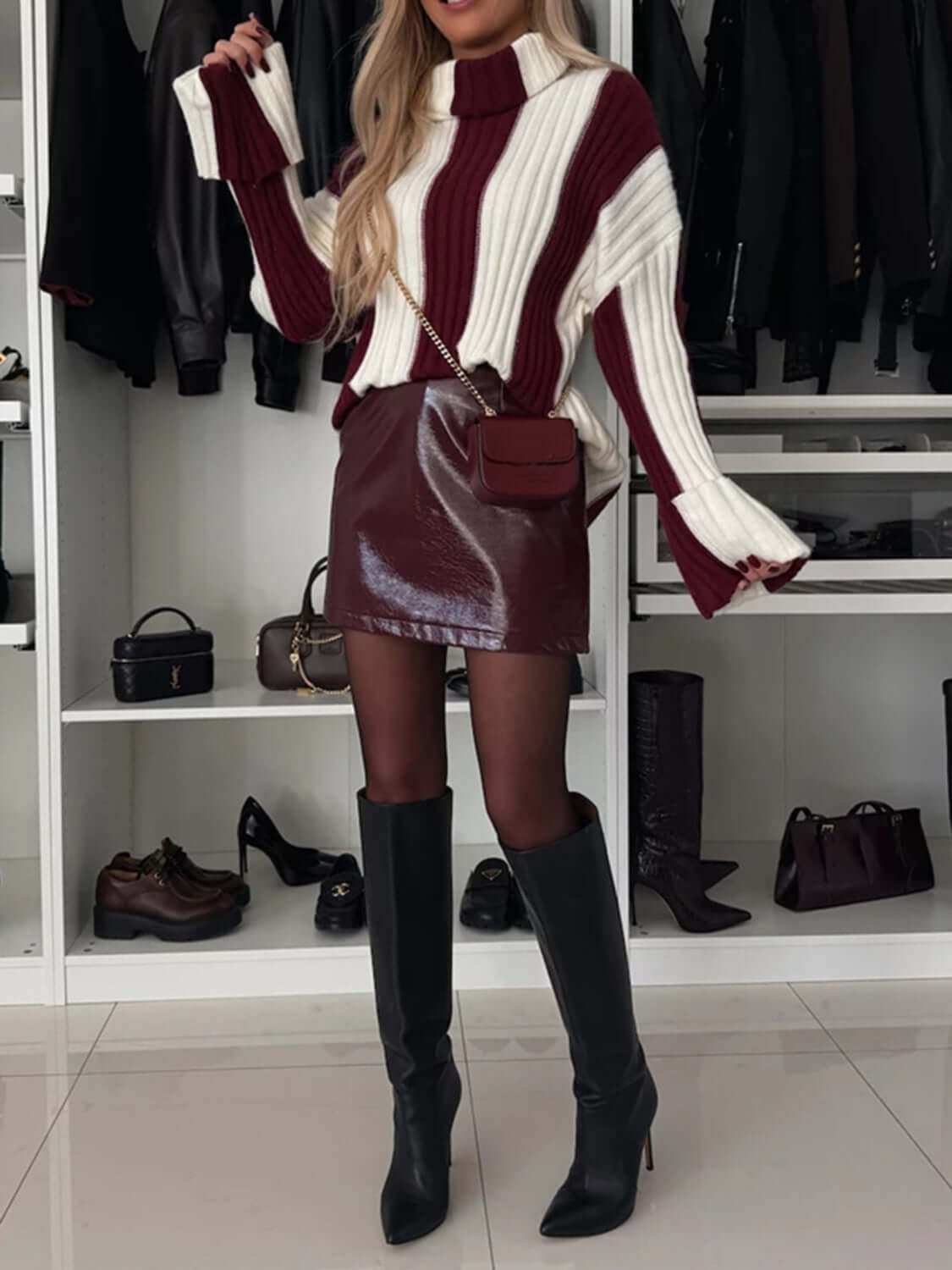 Striped turtleneck dropped shoulder sweater with burgundy and white stripes styled with a leather skirt and knee-high boots.