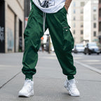 Men’s streetwear cargo pants with multiple pockets and drawstring waist by FitiqueFit, shown in a casual outdoor setting.