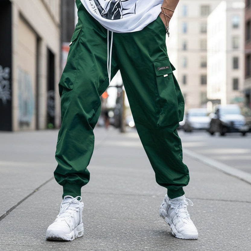 Men’s streetwear cargo pants with multiple pockets and drawstring waist by FitiqueFit, shown in a casual outdoor setting.