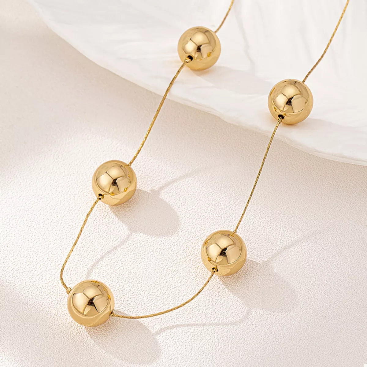 Golden sphere statement necklace with bold round pendants, stylish jewelry piece from Plush Fashion Hub.