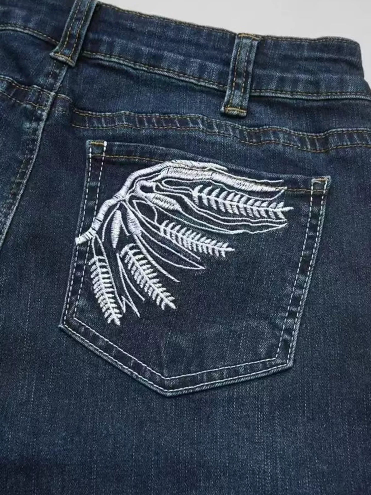 Wings embroidered high-rise cargo jeans from Trendsi featuring functional pockets and embroidered wing design on denim.