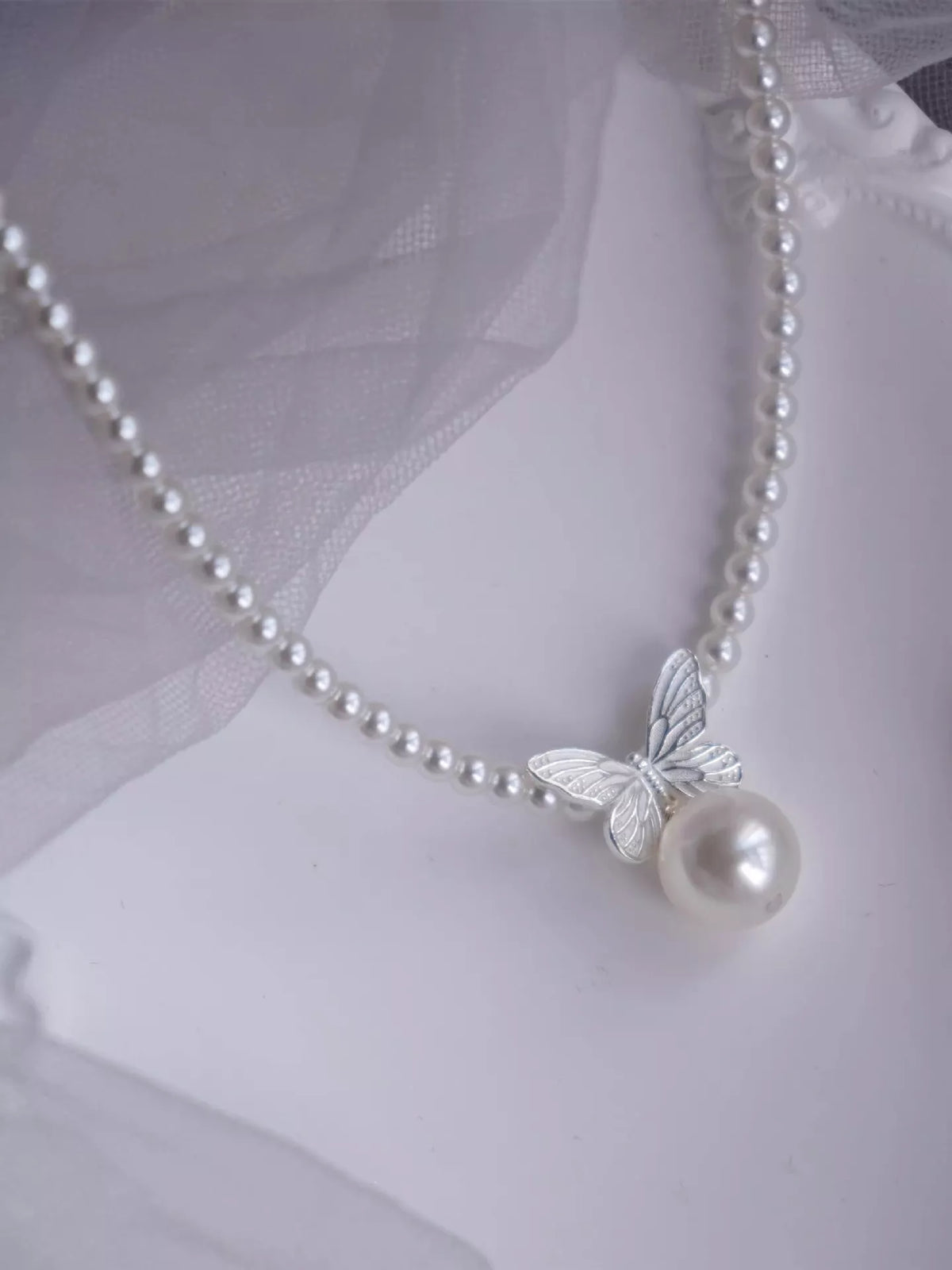 Pearl butterfly pendant necklace featuring a delicate white pearl and silver butterfly charm, stylish jewelry from Plush Fashion Hub.