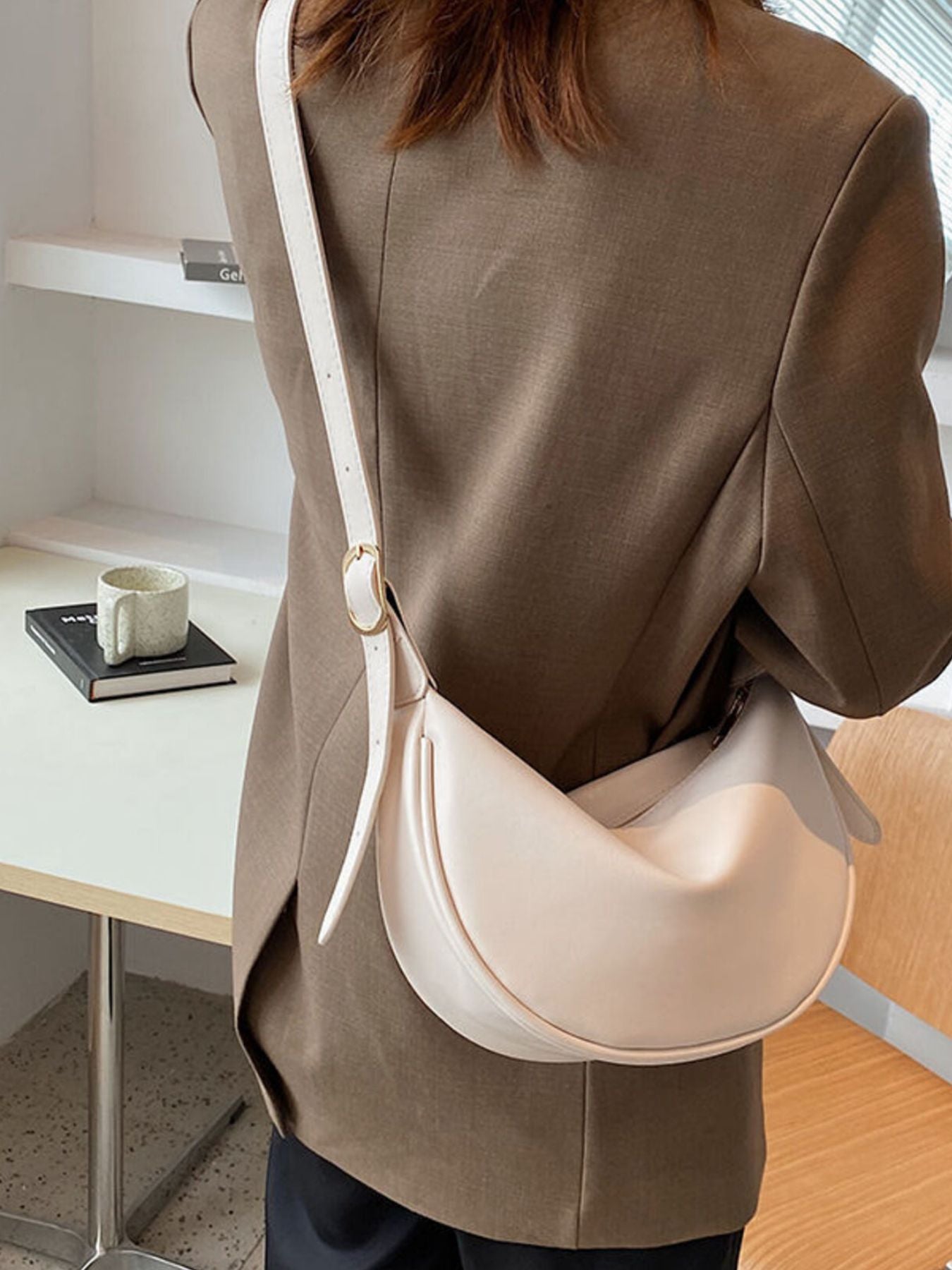 Minimalist crescent-shaped crossbody bag in smooth PU leather, shoulder purse style with sleek, modern design.