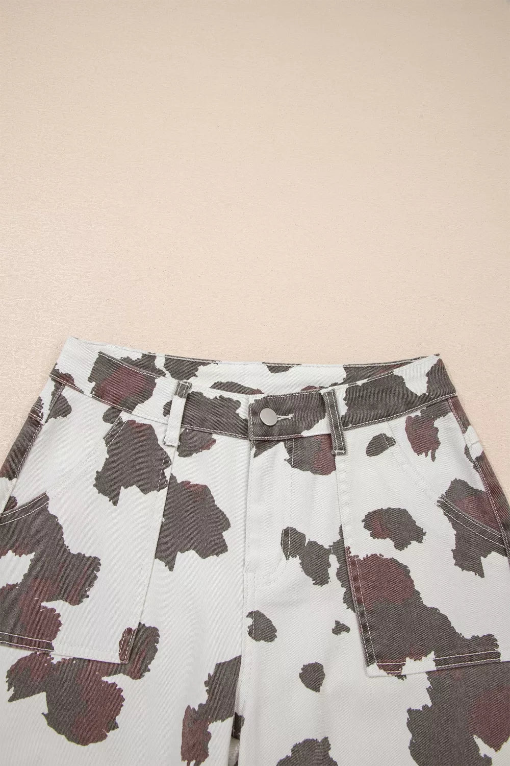 Cow spots printed multi-pocketed jeans by Plush Fashion Hub, featuring a playful cow print pattern and multiple functional pockets.