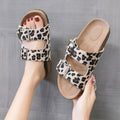 Leopard print double-buckle slide sandals with beige cork-style footbeds and silver hardware.