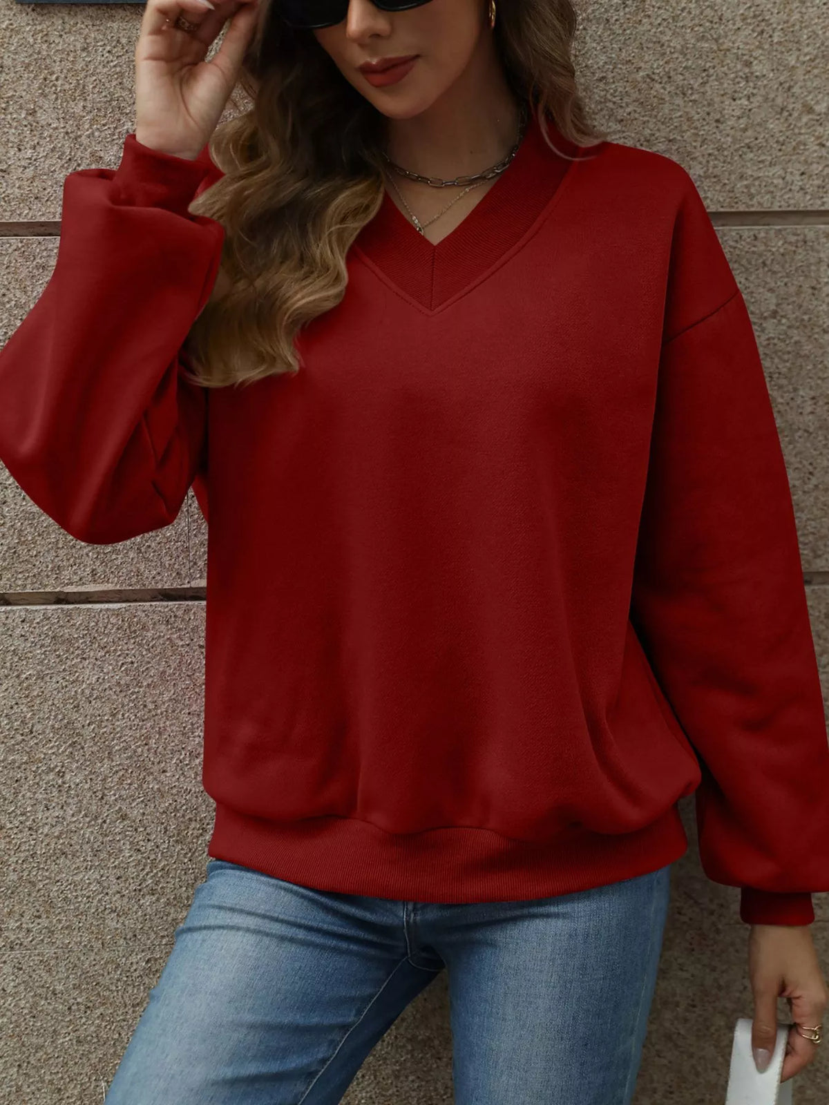 V-neck solid color casual sweatshirt by Trendsi with long sleeves and relaxed fit, displayed on a hanger.
