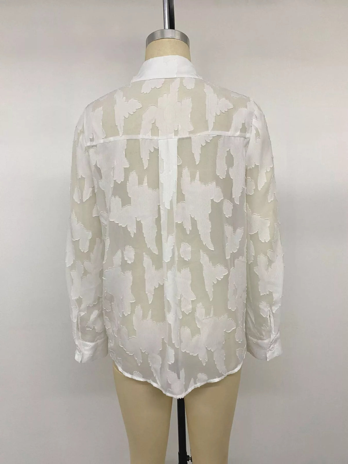 Sheer button-down shirt by Trendsi featuring long sleeves, collar, and lightweight transparent fabric, ideal for layered styling.