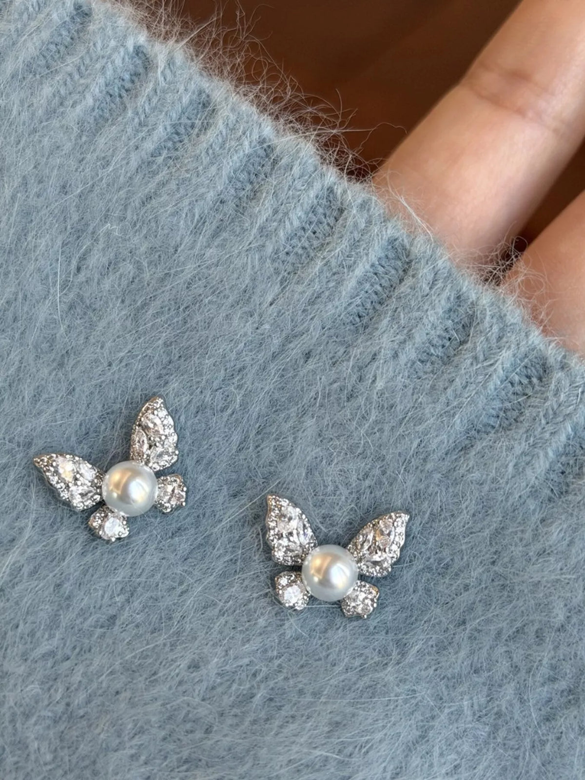Pair of butterfly-shaped pearl stud earrings from Plush Fashion Hub, featuring elegant white pearls on silver posts.