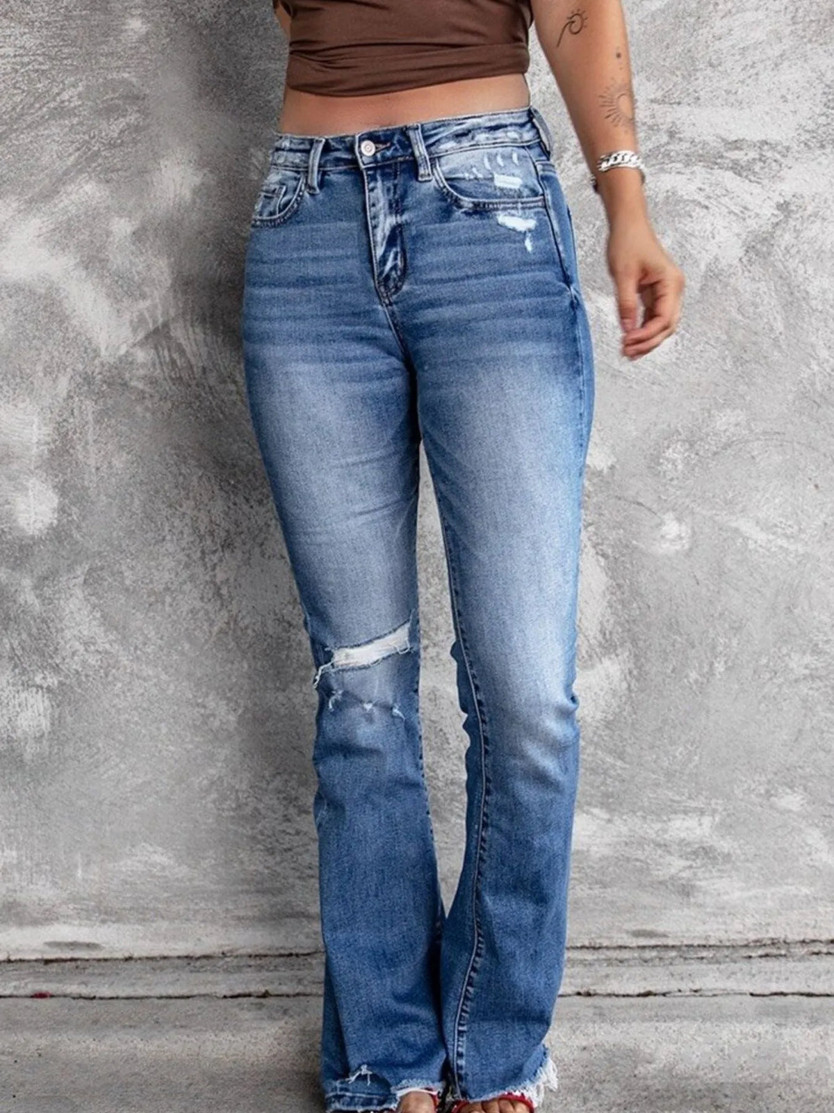 Distressed flare denim jeans by Plush Fashion Hub featuring ripped details and a high-waist fit on a model.