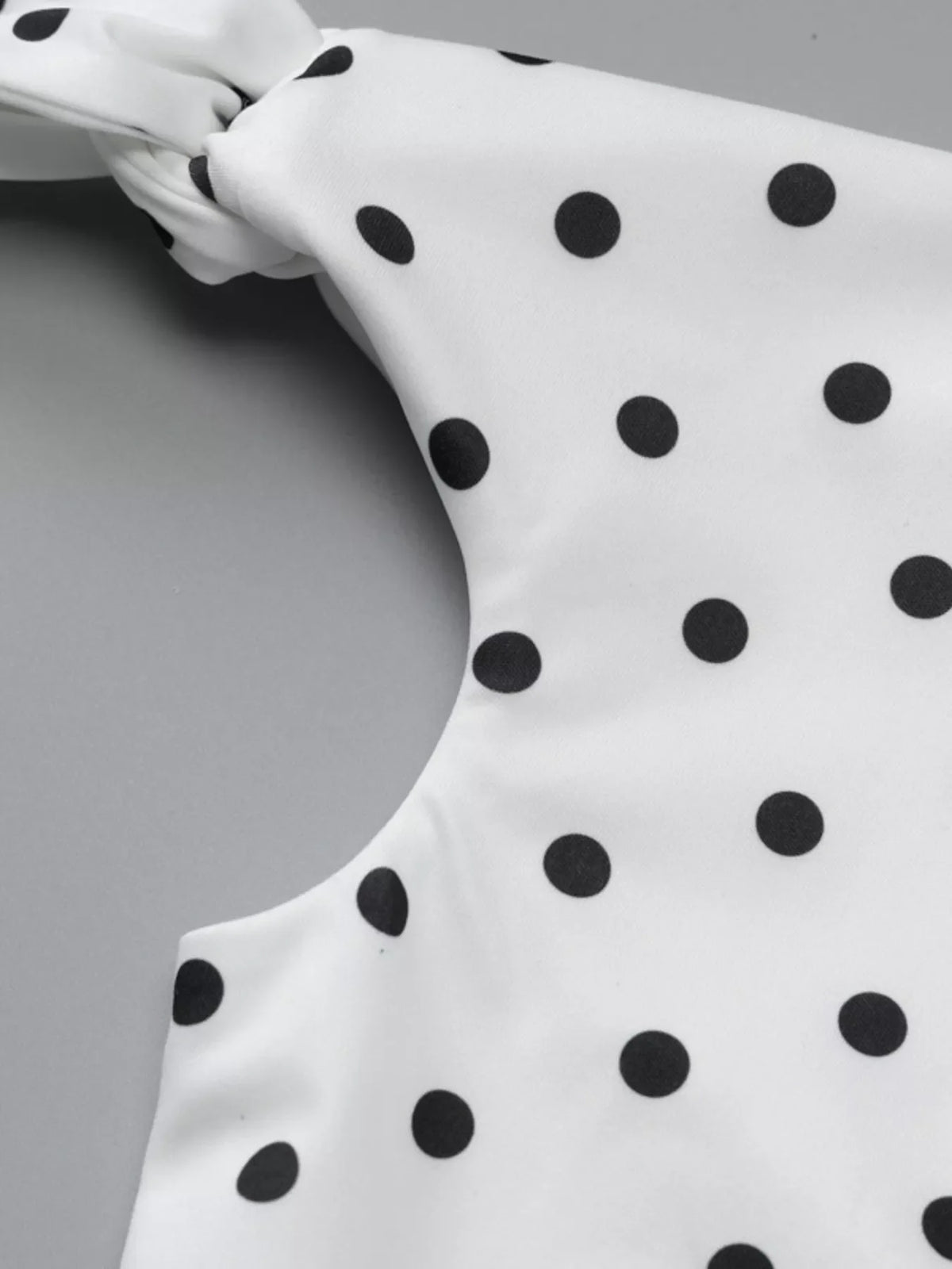 Polka dot sleeveless mini dress with bow accents by Plush Fashion Hub, featuring a playful and stylish design perfect for summer wear.