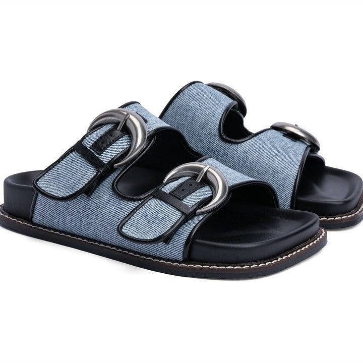 Light blue denim sandals with two straps, oversized silver buckles, black leather trim, and a contoured footbed.