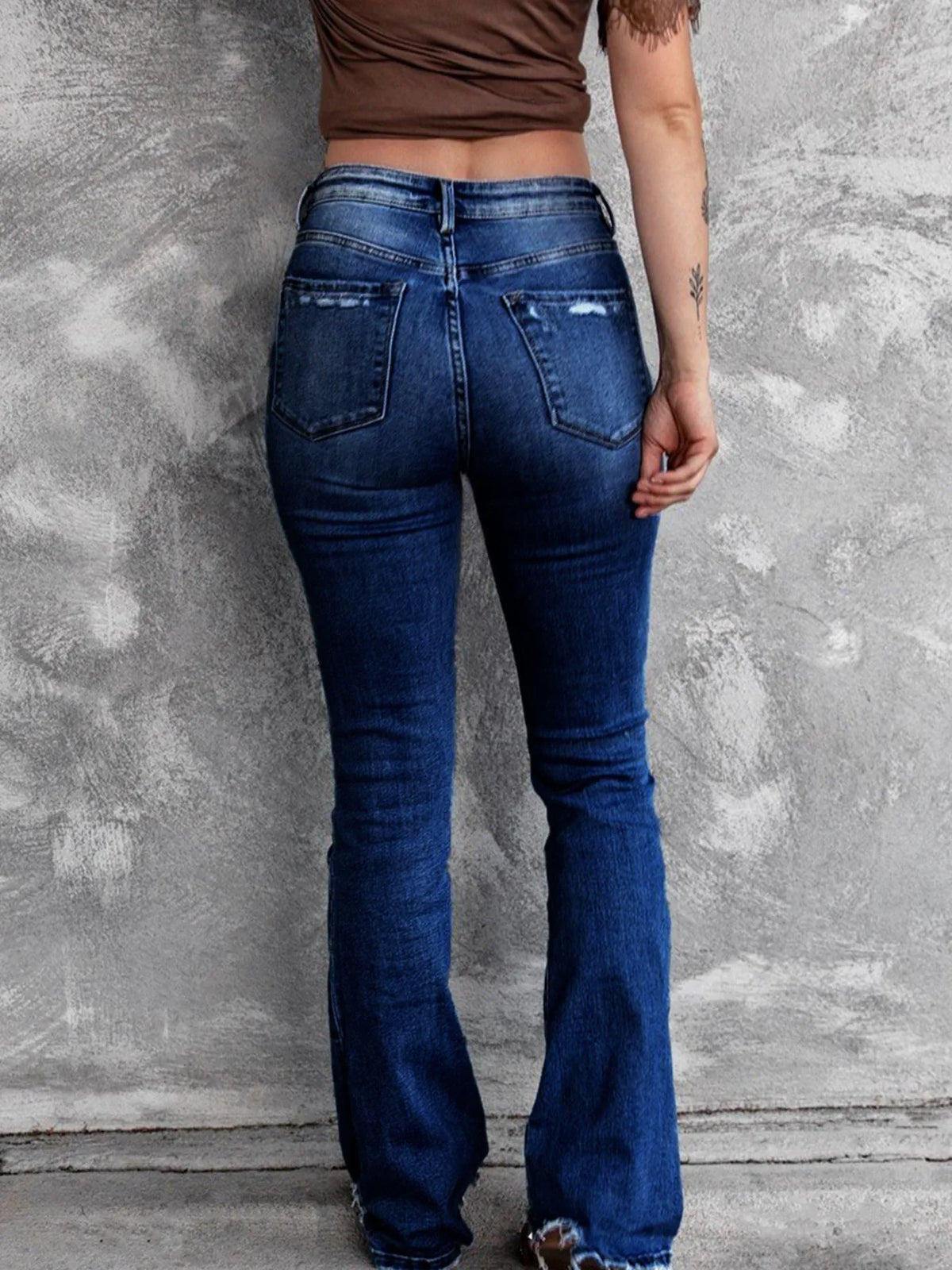 Distressed flare denim jeans by Plush Fashion Hub featuring ripped details and a high-waisted fit on a model.