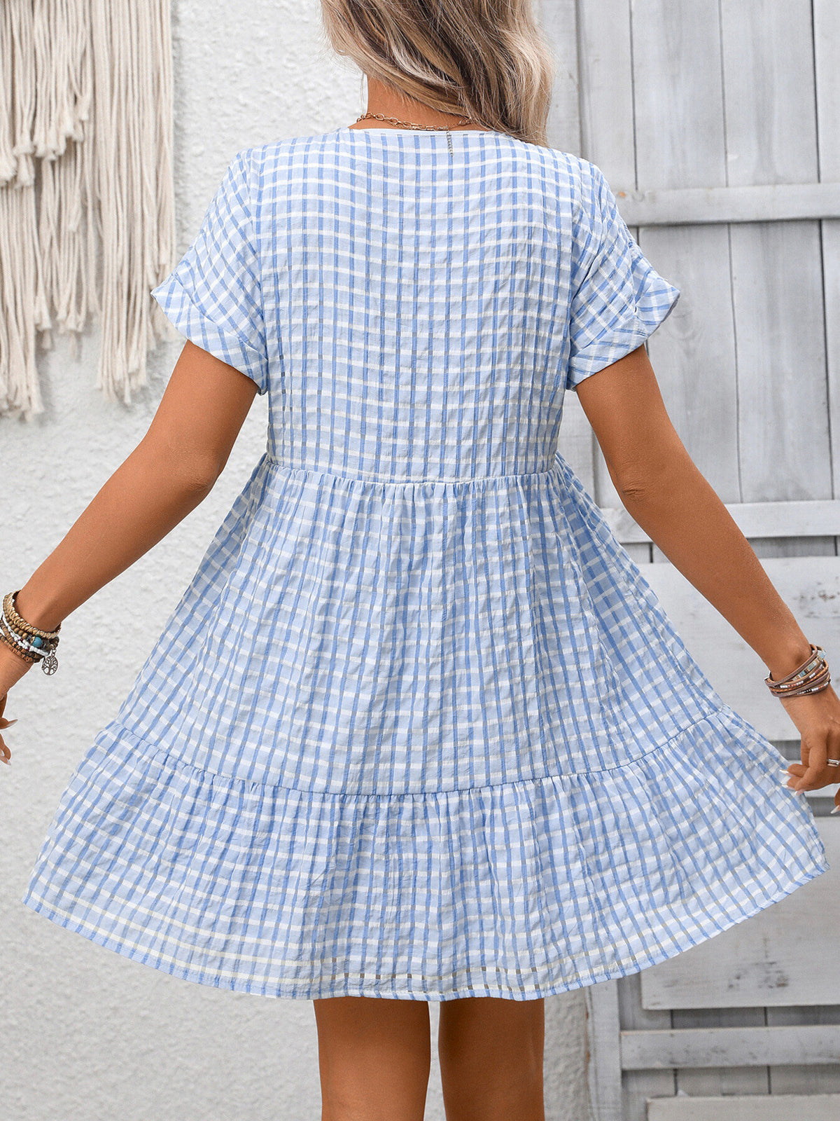 Chic plaid V-neck mini dress with ruffle hem by Plush Fashion Hub, featuring a stylish pattern and feminine design.