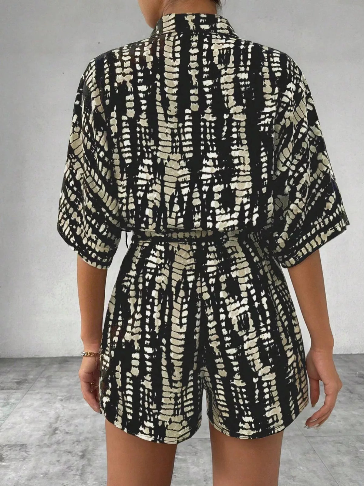 Striped button-up belted romper jumpsuit by Plush Fashion Hub, featuring a stylish design with a collar and waist tie.