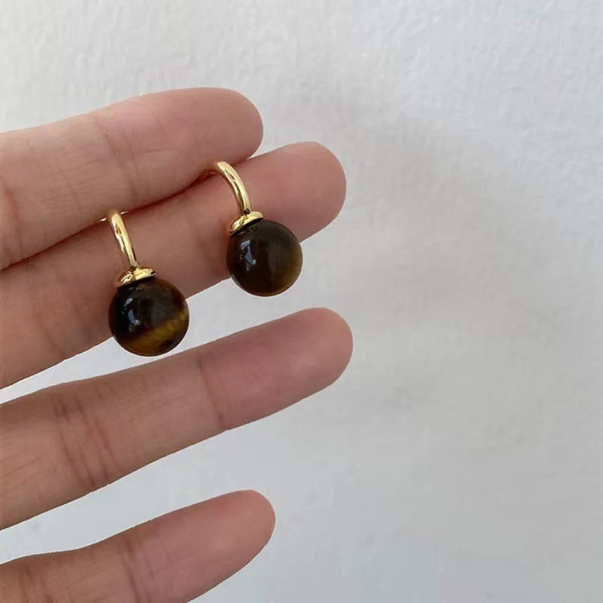 Tiger Eye ball drop earrings from Plush Fashion Hub featuring polished gold-tone hooks and smooth oval tiger eye beads.