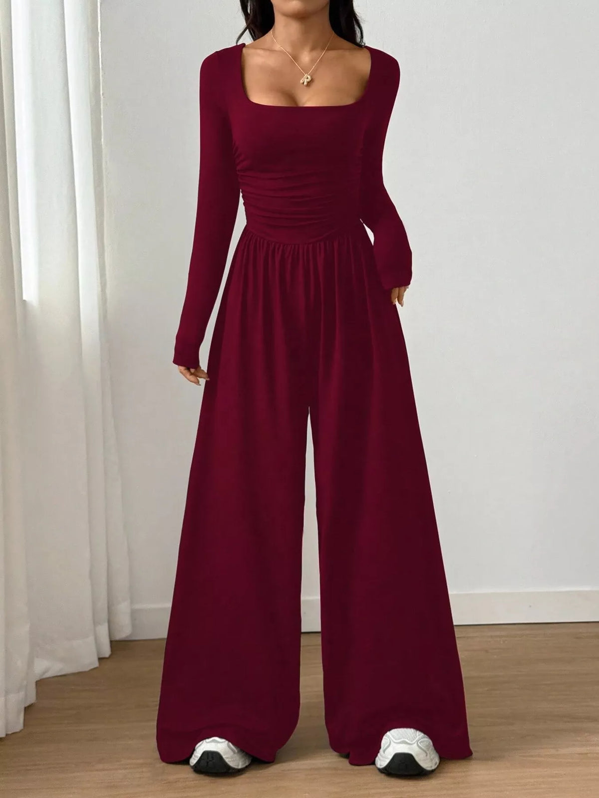 Black ruched square neck wide-leg jumpsuit by Trendsi, featuring a fitted bodice and flowy pant legs, styled for a chic look.