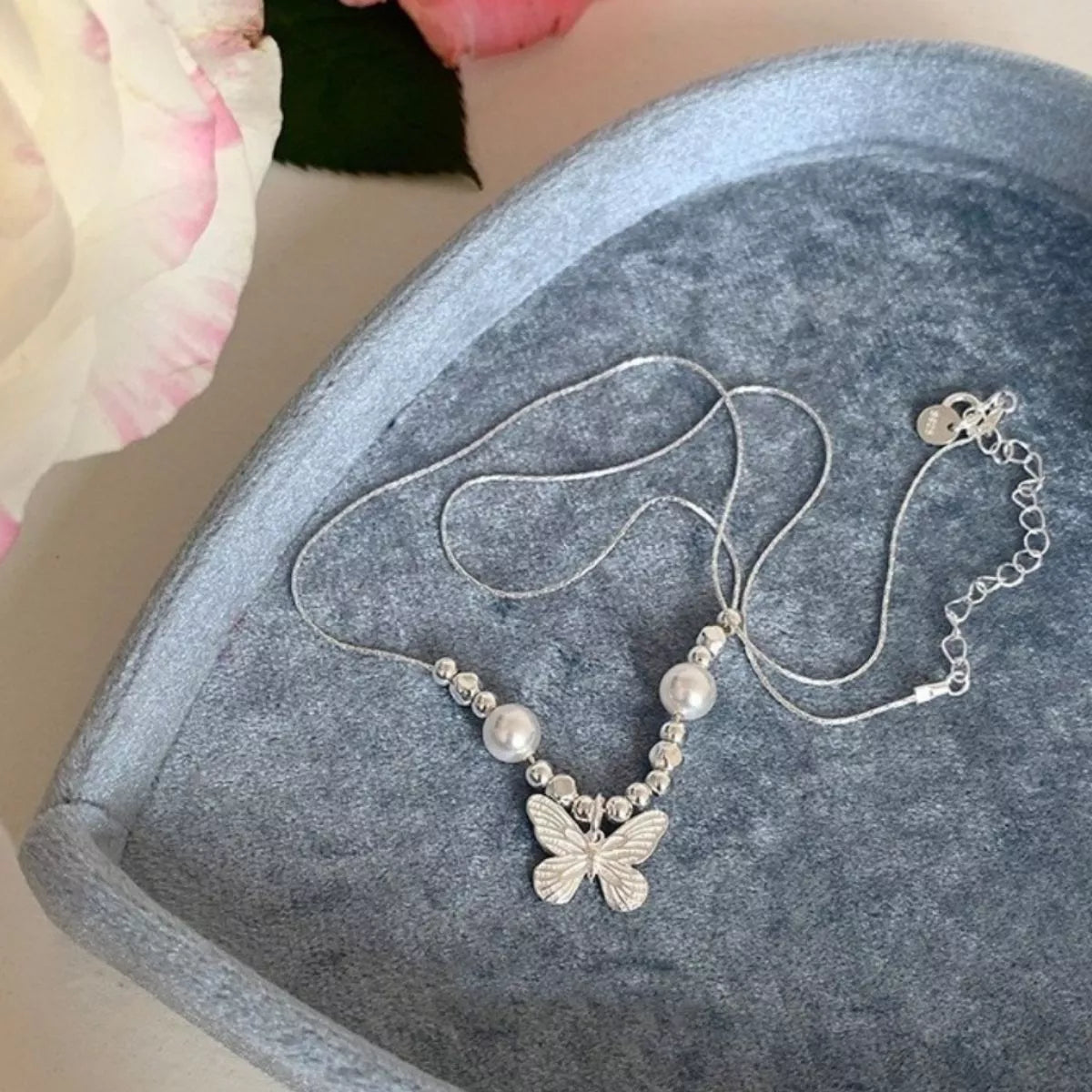 Butterfly pearl pendant necklace from Plush Fashion Hub featuring a delicate pearl and butterfly charm on a silver chain.