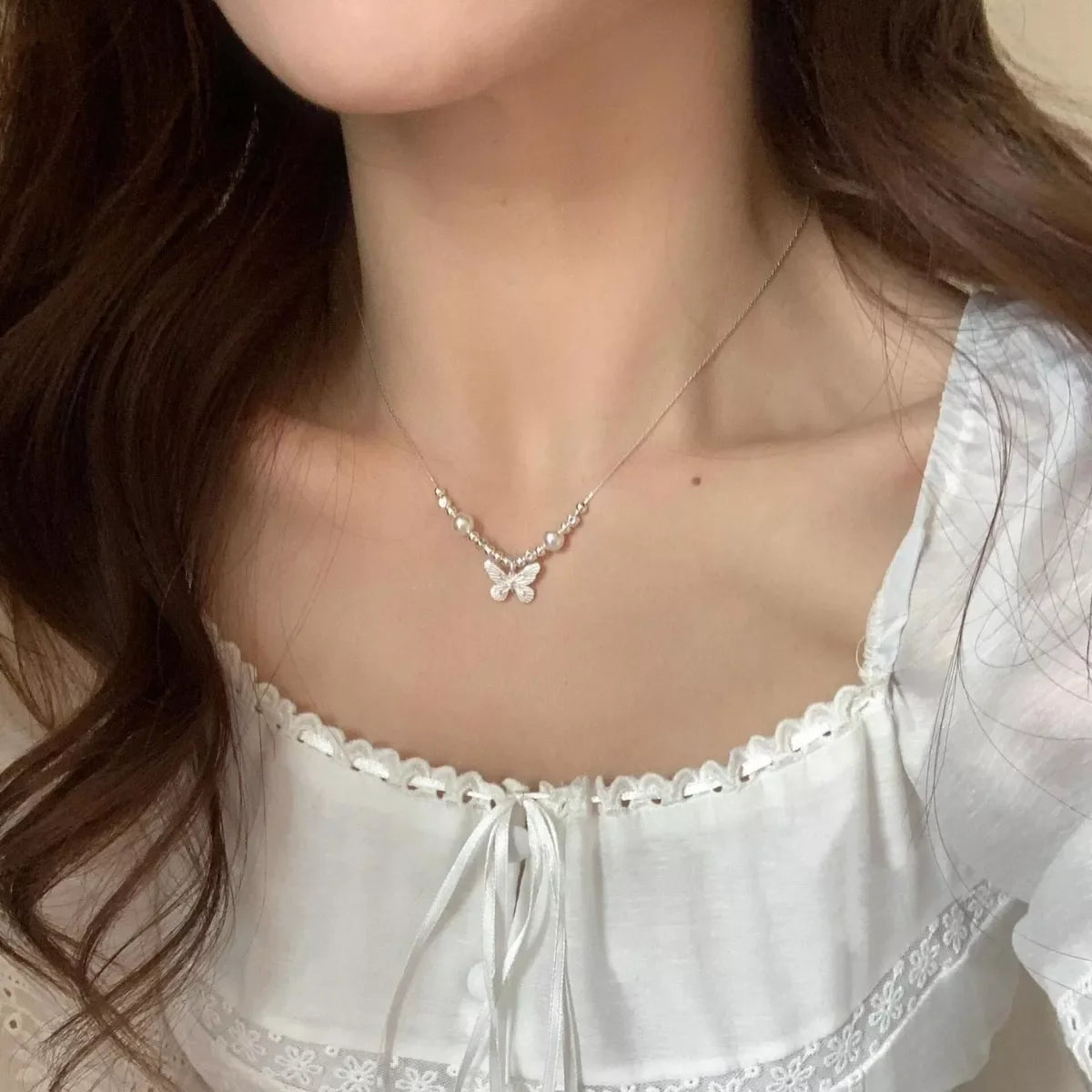 Butterfly pearl pendant necklace with silver chain, featuring a delicate butterfly and pearl charm, stylish jewelry accessory.