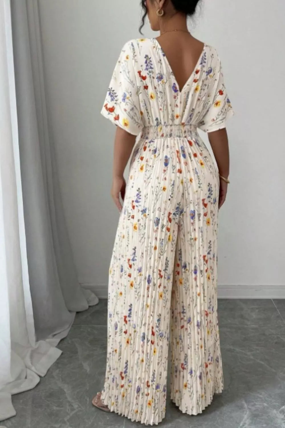 Floral print wide-leg pleated jumpsuit by Plush Fashion Hub featuring a fitted waist and flowing wide-leg design.
