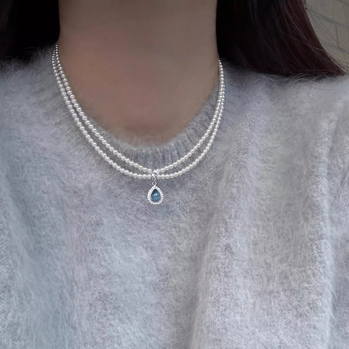 Double layered pearl necklace with teardrop pendant, featuring elegant white pearls and a silver chain from Plush Fashion Hub.