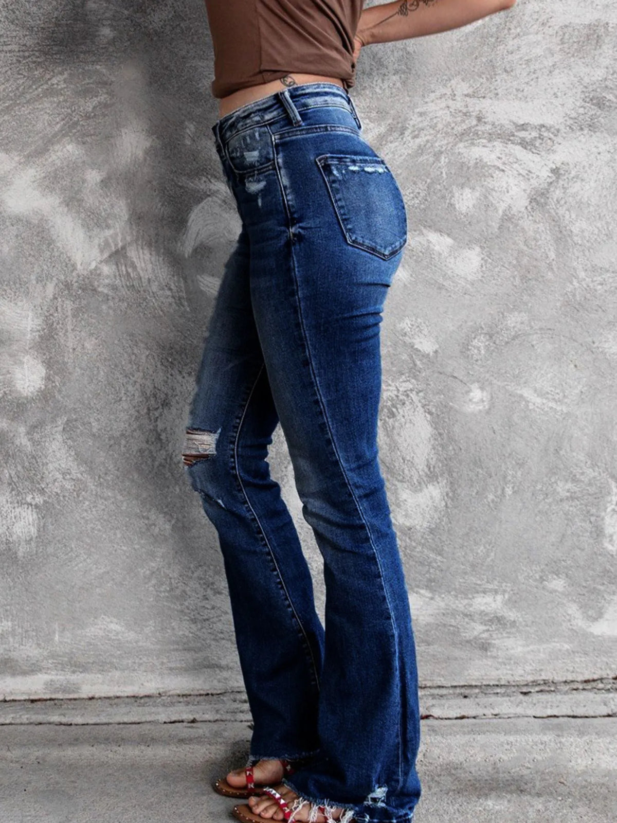 Distressed flare denim jeans by Plush Fashion Hub featuring ripped details and a high-waist fit, styled with casual footwear.