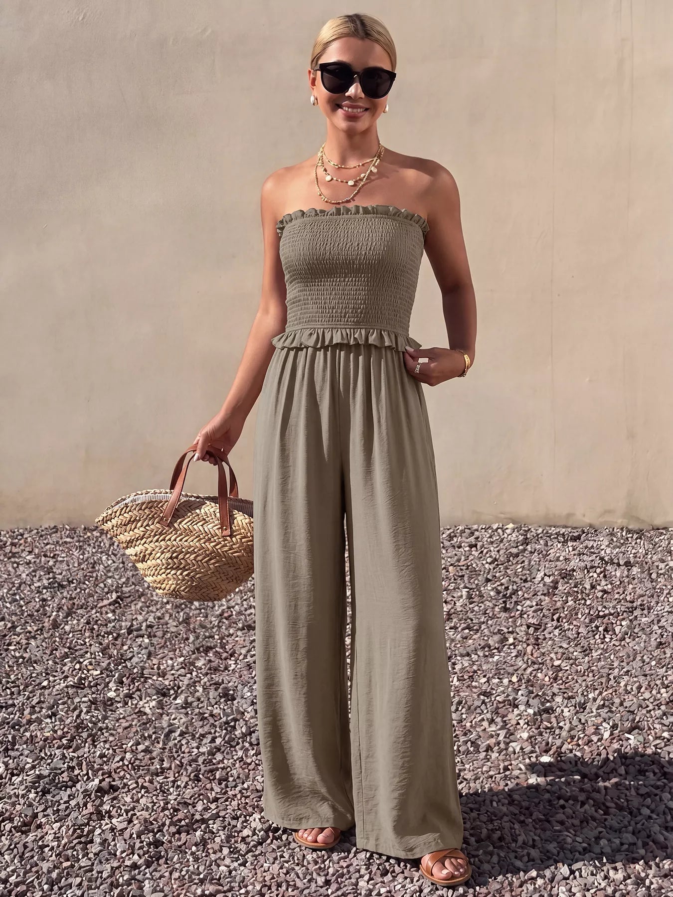 Smocked strapless wide-leg jumpsuit by Trendsi featuring a fitted bodice and flowing wide-leg pants, displayed on a hanger.