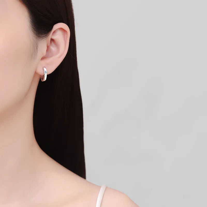Sterling silver moissanite huggie earrings featuring sparkling gemstones, designed for a stylish and elegant look.