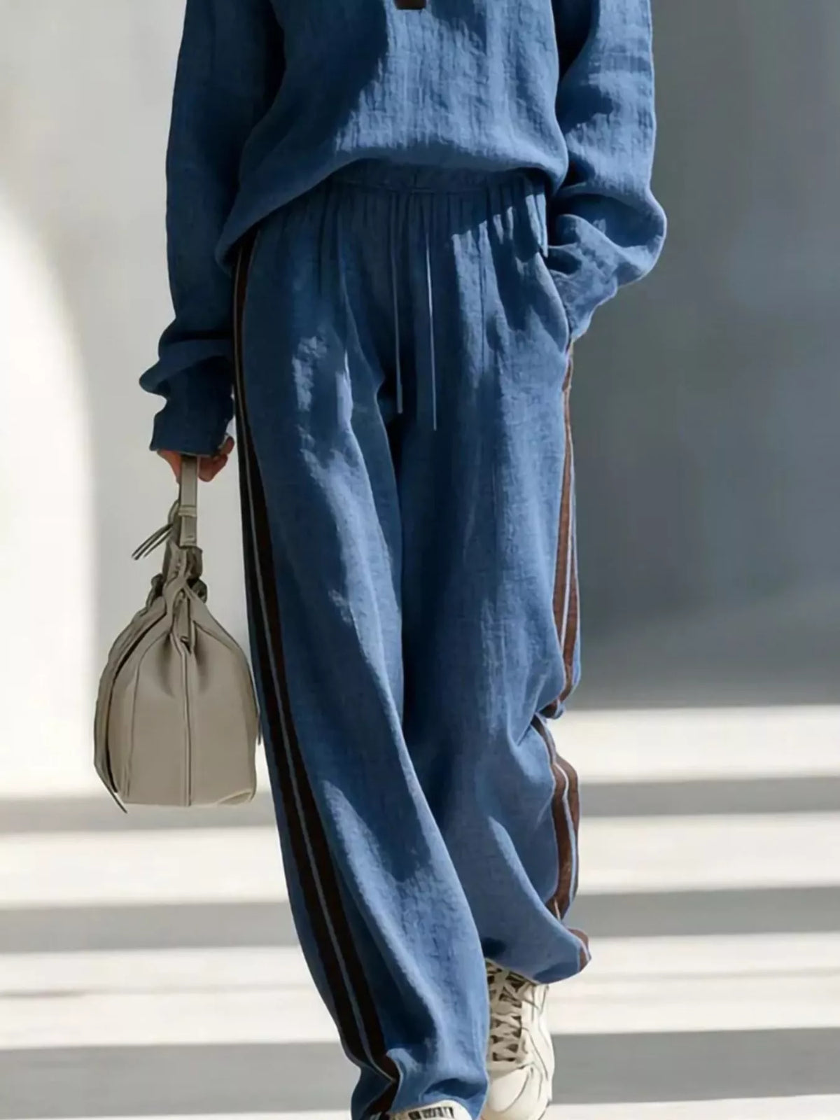 Women's contrast V-neck top and striped pants set, trendy fashion ensemble by Trendsi, shown in stylish natural pose.