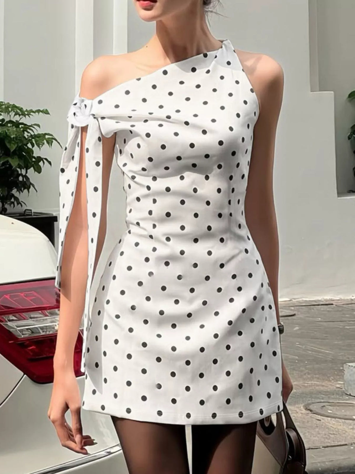 Polka dot sleeveless mini dress with bow accents by Plush Fashion Hub, featuring a fitted bodice and playful polka dot pattern.
