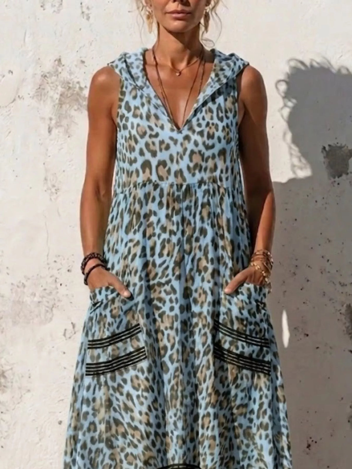 Plus size leopard print sleeveless hooded maxi dress with pockets, featuring a flowing silhouette and bold animal print design.