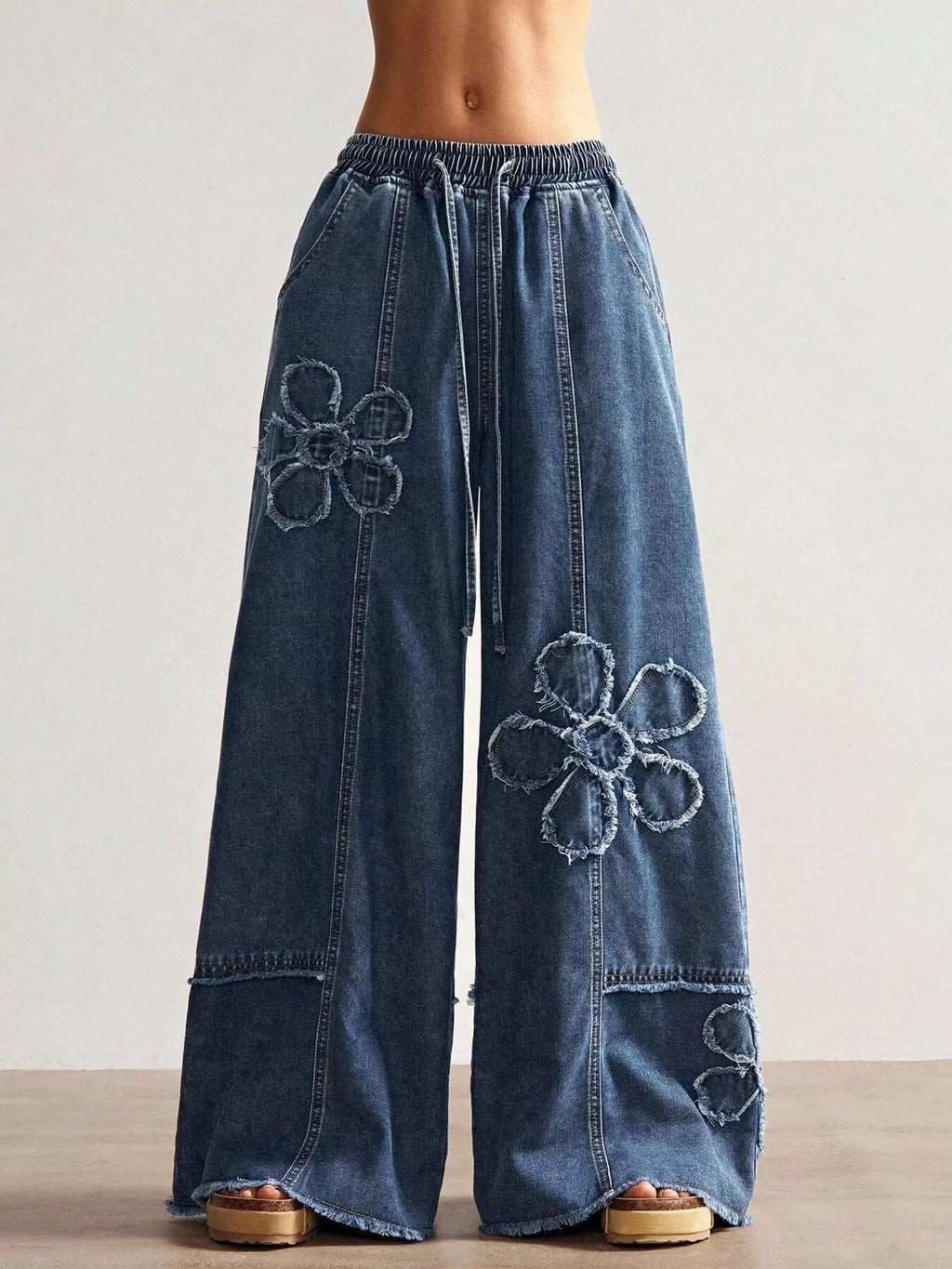 Wide leg jeans with floral appliques by Shopimist, featuring detailed floral embroidery on denim fabric.