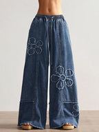 Wide leg jeans with floral appliques by Shopimist, featuring detailed floral embroidery on denim fabric.