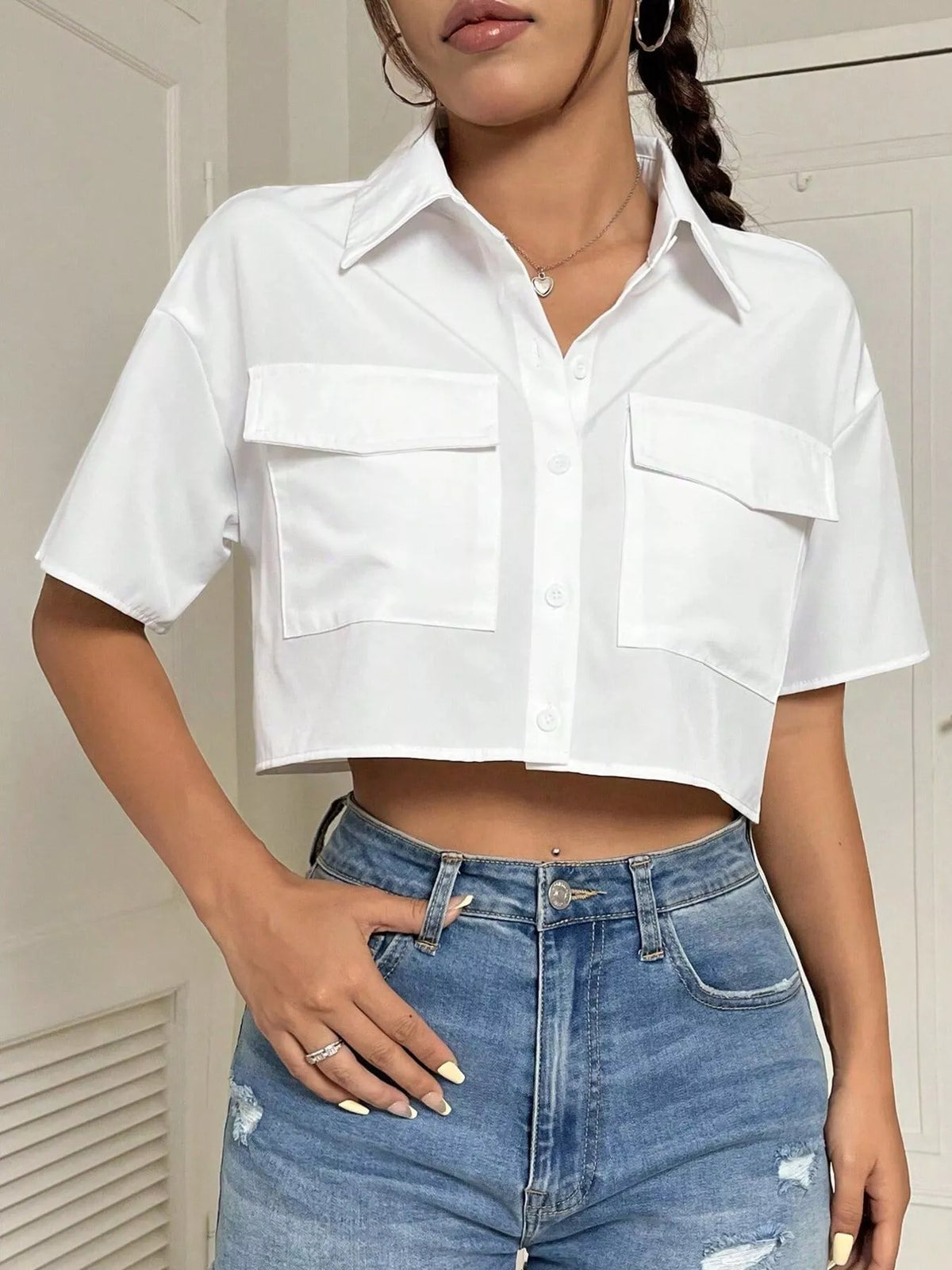 Short sleeve crop shirt with chest pockets, trendy casual top from Trendsi, shown in a stylish, fitted design with button closure.