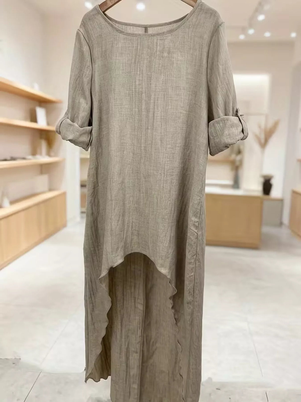 High-low hem blouse with roll-up sleeves from Trendsi, featuring a stylish and flowy design ideal for casual or dressy occasions.