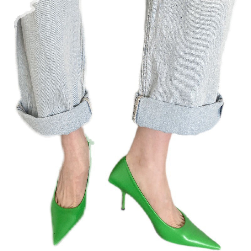 Bright green pointed-toe faux leather stiletto pumps worn with cuffed light-wash denim jeans.