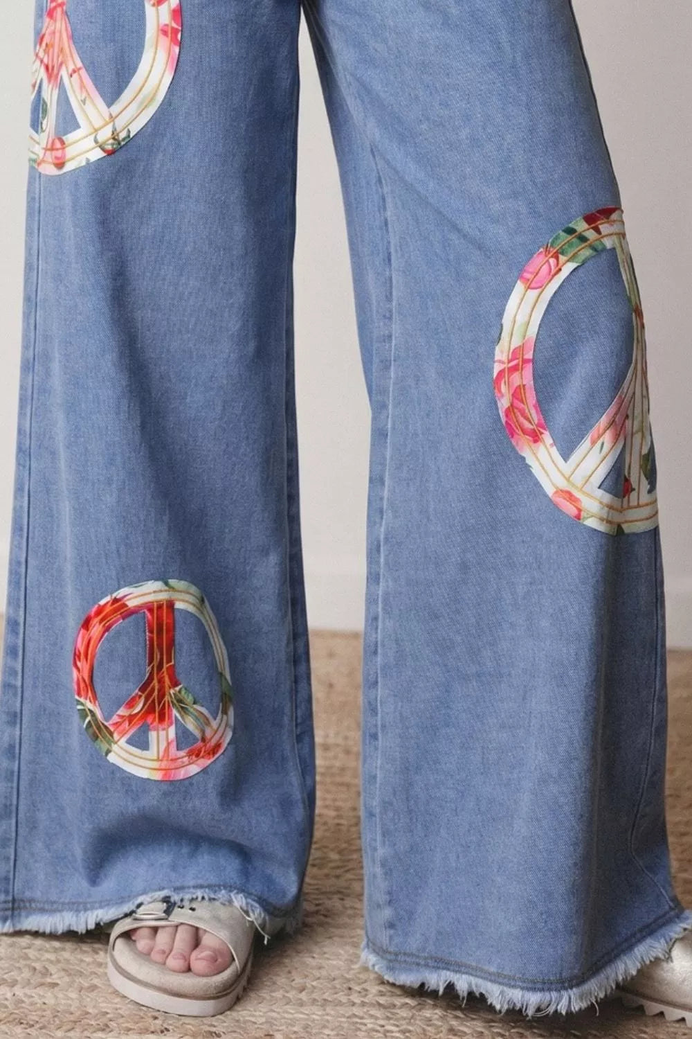Floral peace sign wide leg jeans by Trendsi featuring a colorful floral peace sign print on relaxed denim.