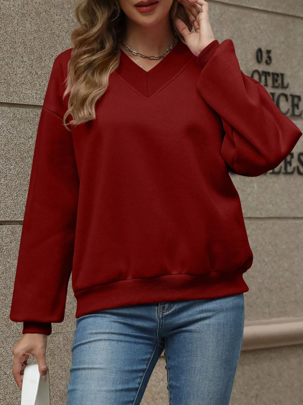 V-neck solid color casual sweatshirt by Trendsi, featuring a relaxed fit and soft fabric, displayed on a hanger.