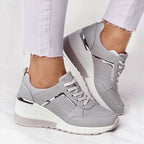 Grey perforated mesh platform sneakers with white soles and metallic silver accents, styled with white jeans.