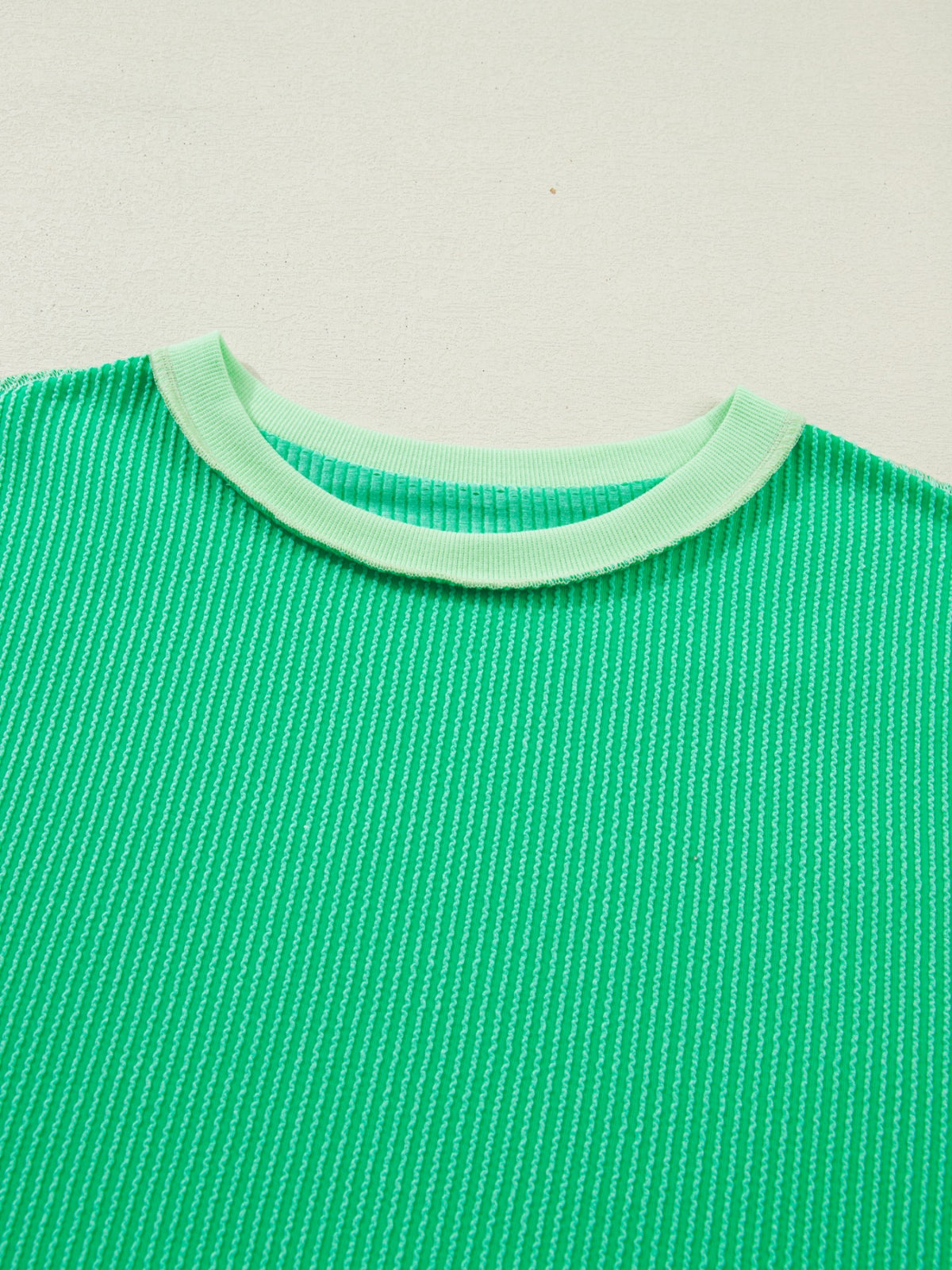 Women’s ribbed short sleeve T-shirt with twist hem and contrast stitching by Plush Fashion Hub, featuring a fitted design.