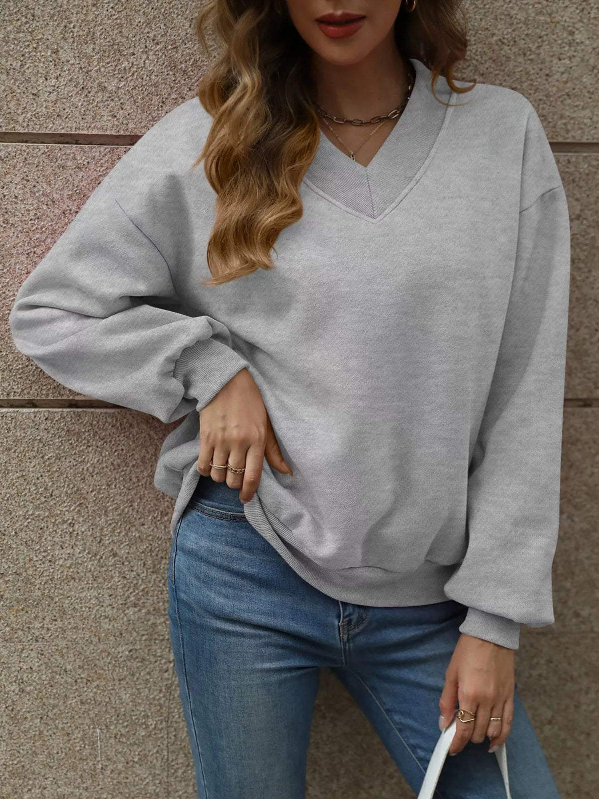 V-neck solid color casual sweatshirt from Trendsi, featuring a relaxed fit and soft fabric, displayed on a hanger.