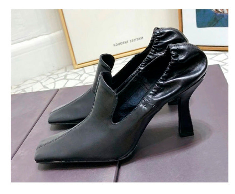 Black leather stiletto mules with a square toe and ruched elasticized collar detail, set on a sculptured heel.