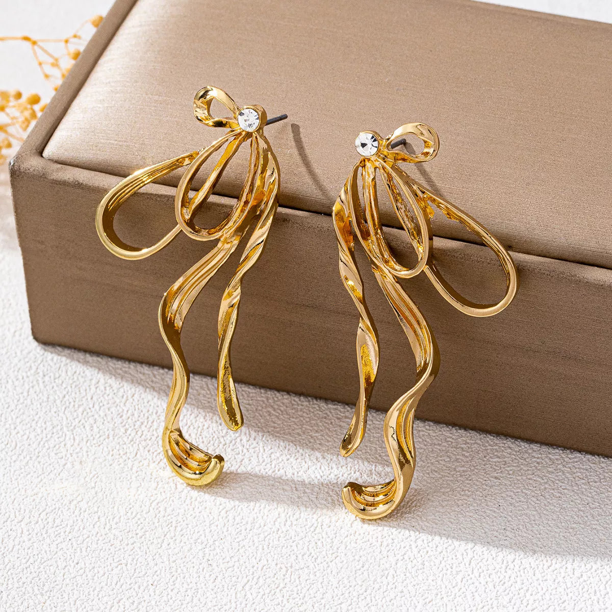 Gold-plated bow earrings from Plush Fashion Hub, showcasing delicate design and shiny finish on a white background.