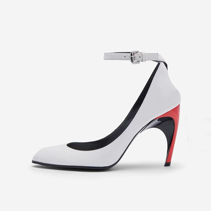 White pointed-toe leather stiletto with an ankle strap, buckle, and colorblock red and black sculptural heel.