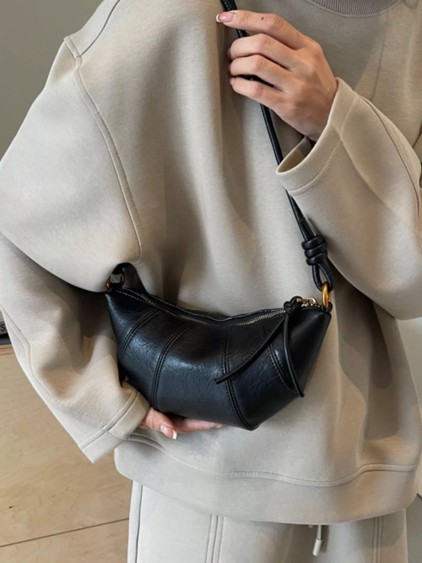 Croissant-shaped crossbody bag from Trendsi, featuring a soft, rounded design with a strap for versatile carrying.