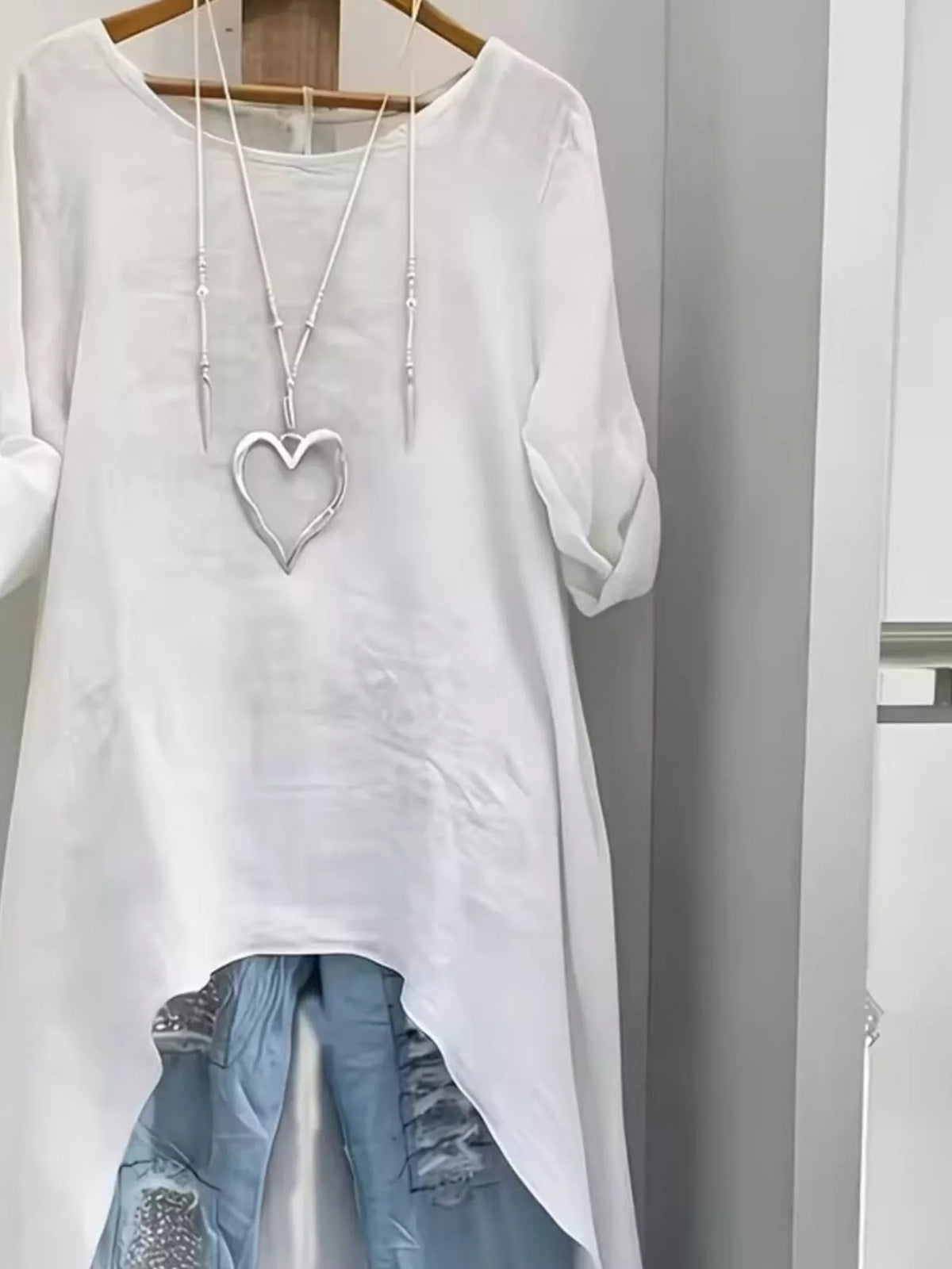 High-low hem roll-up sleeves blouse by Trendsi featuring a stylish, flowy design with adjustable sleeve tabs and a relaxed fit.