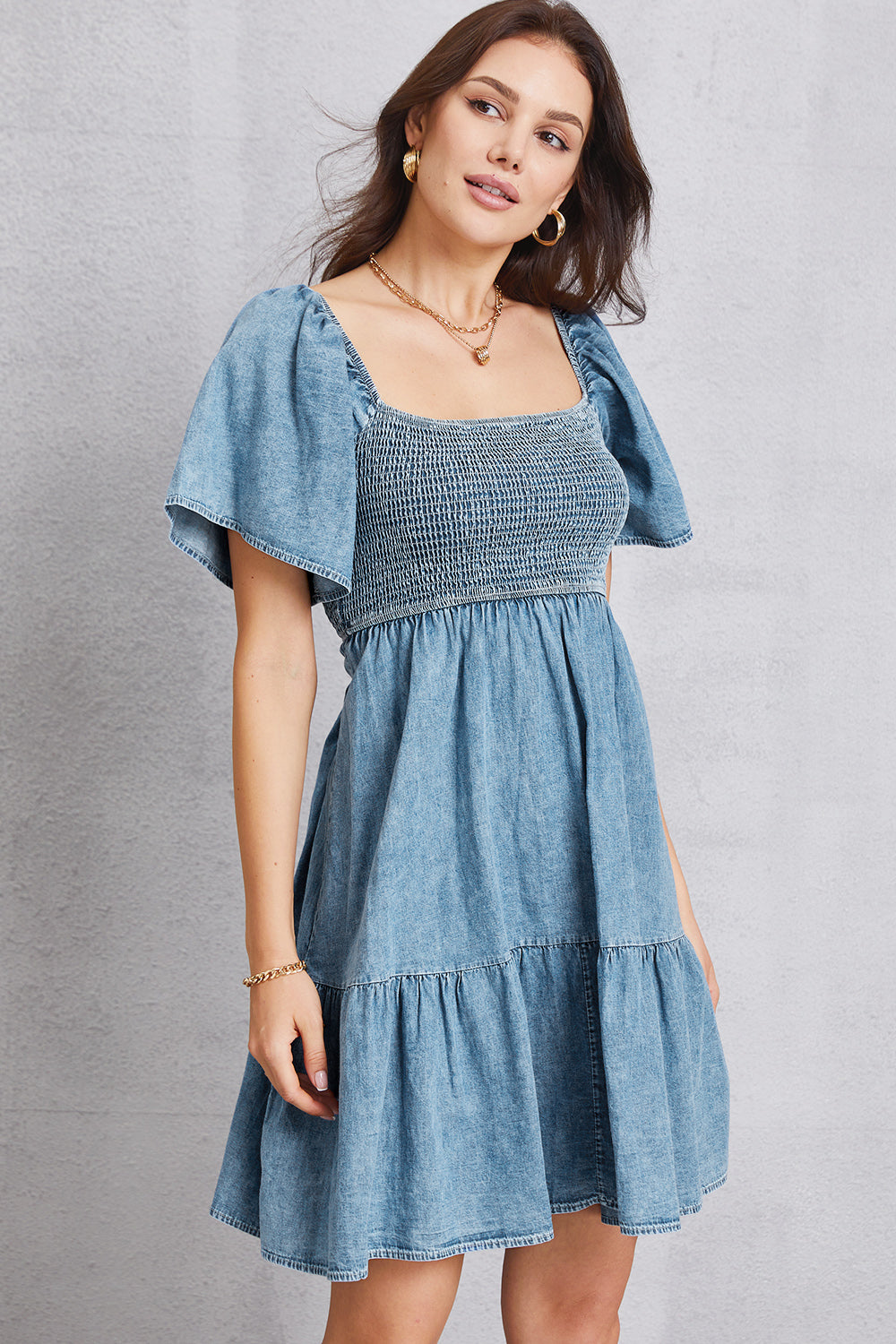 Smocked square neck mini denim dress by Plush Fashion Hub, showing the dress's fitted bodice and sleeveless design on a hanger.
