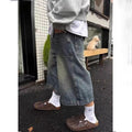 Vintage distressed wide-leg denim shorts in a faded blue wash, featuring front utility pockets and a loose fit.