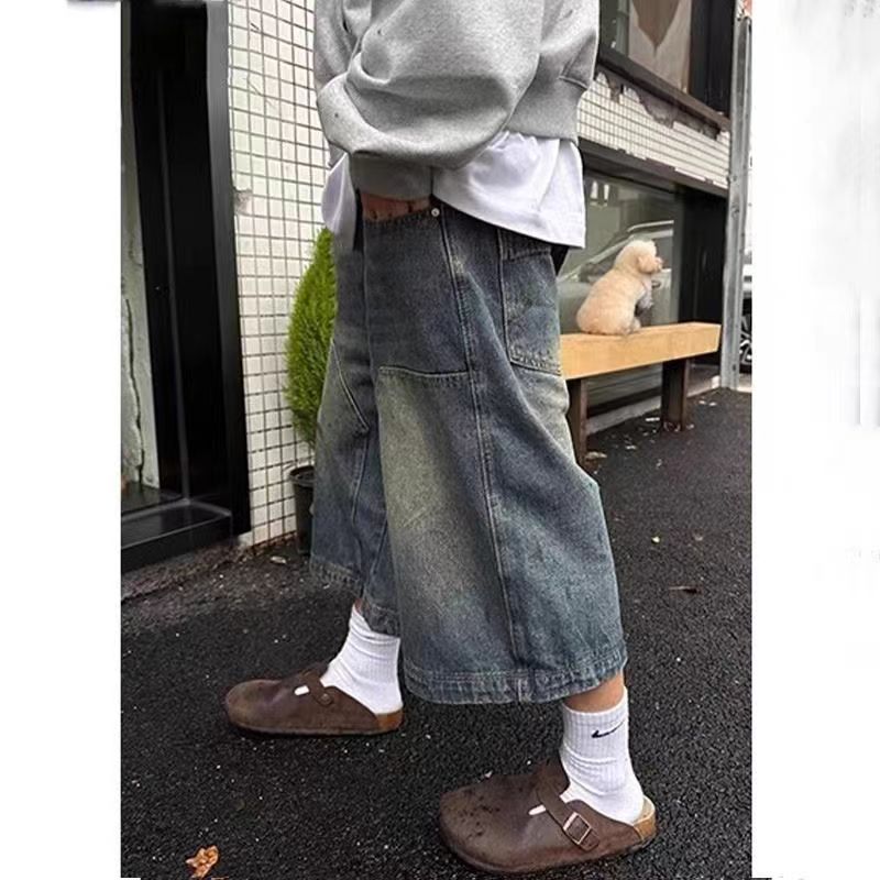 Vintage distressed wide-leg denim shorts in a faded blue wash, featuring front utility pockets and a loose fit.